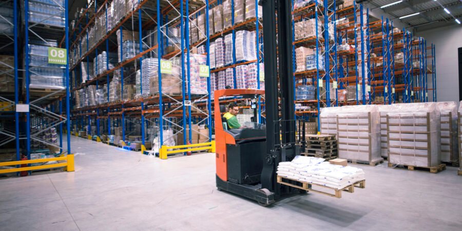 Worker operating forklift machine and relocating goods in large warehouse center. استئجار أدوات يدوية الباحة - باب رزق ثقيل